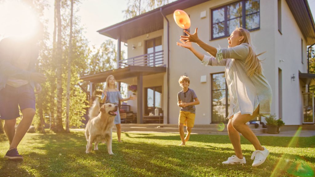 Glückliche Familie spielt im Garten vor Ihrem neuen zu Hause