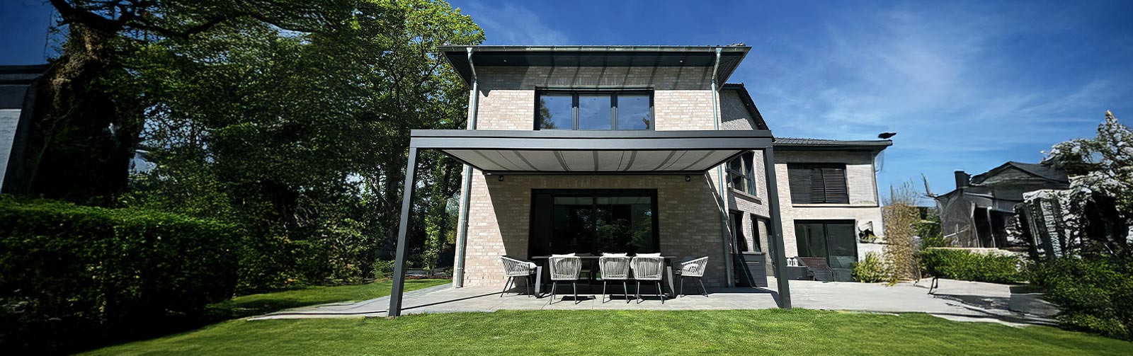 Blick auf Haus mit großem abgeschatteten Sitzbereich als Terasse zum großen Garten hin.
